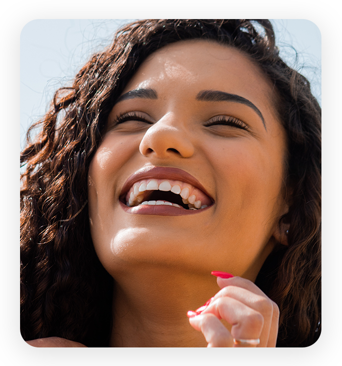image 1 A woman with curly hair smiling and holding her hand to the side.