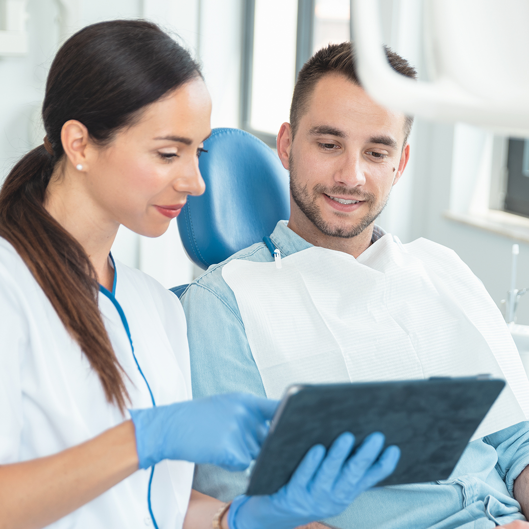 text-img2 A dentist showing a patient something on his tablet.